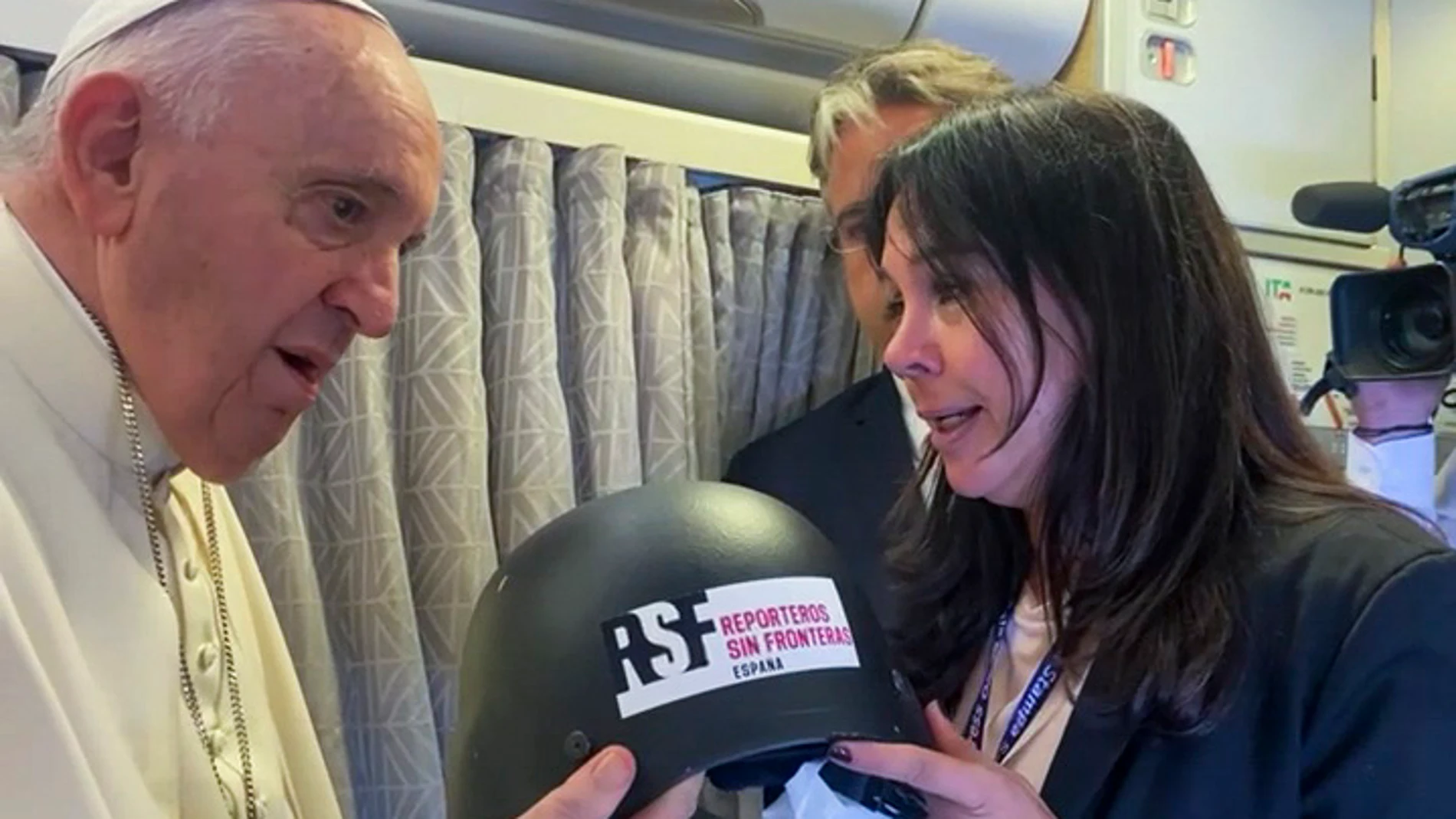 Captura de video del momento en el que el papa Francisco recibió hoy durante el vuelo hacia Canadá un casco de los que usó para sus coberturas el periodista español David Beriai