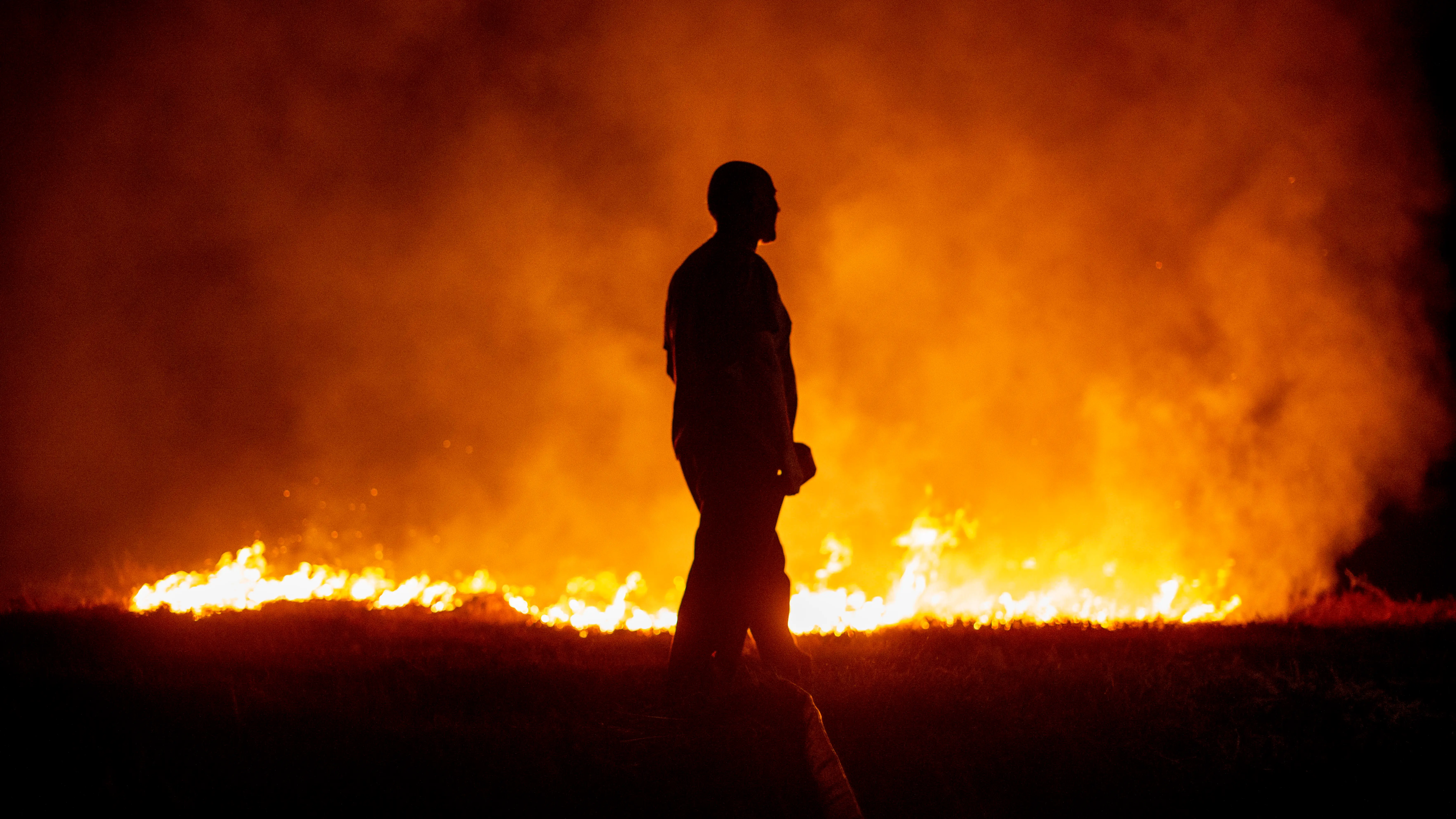 Un vecino ante las llamas mientras colabora en las labores de extinci&oacute;n del incendio de Cures, en Boiro, A Coru&ntilde;a, en la madrugada de este s&aacute;bado.