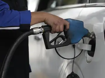 Un hombre pone gasolina a un vehículo Un hombre pone gasolina a un vehículo