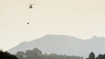 Un helicóptero se dirige cargado con agua hacia el frente del incendio forestal declarado en la Vall d'Ebo (Alicante).