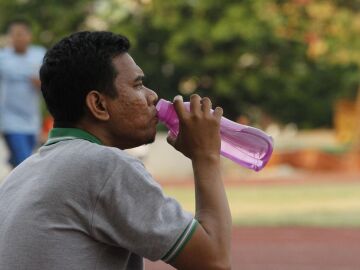Un hombre bebe agua para hidratarse