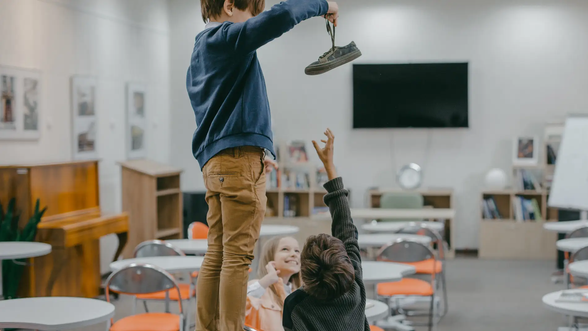 Imagen general de un aula con tres niños, uno de ellos no le quiere devolver el zapato a otro
