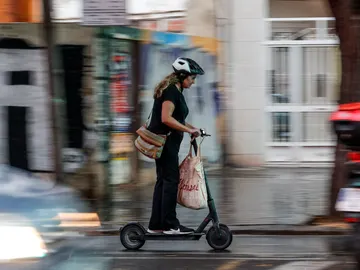 Imagen de archivo de una mujer en un patinete eléctrico Imagen de archivo de una mujer en un patinete eléctrico