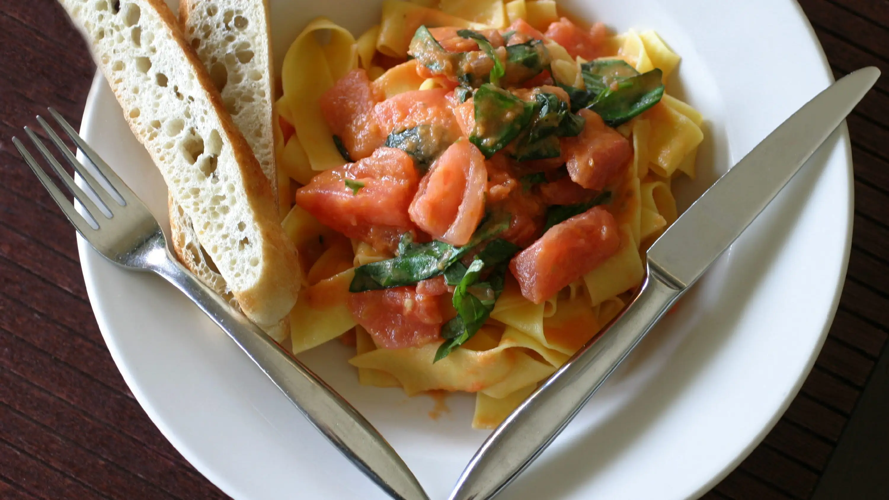 Un plato de pappardelle con tomates y ajo tostado Un plato de pappardelle con tomates y ajo tostado