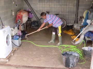 Un vecino limpia parte de su casa tras la intensa tromba de agua