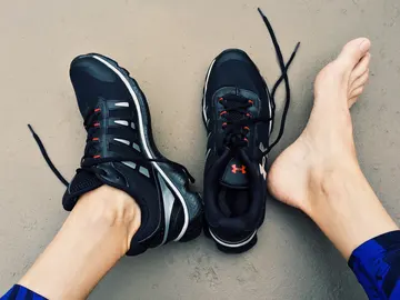 Primer plano de pies, un con una zapatilla deportiva y otro desnudo Primer plano de pies, un con una zapatilla deportiva y otro desnudo
