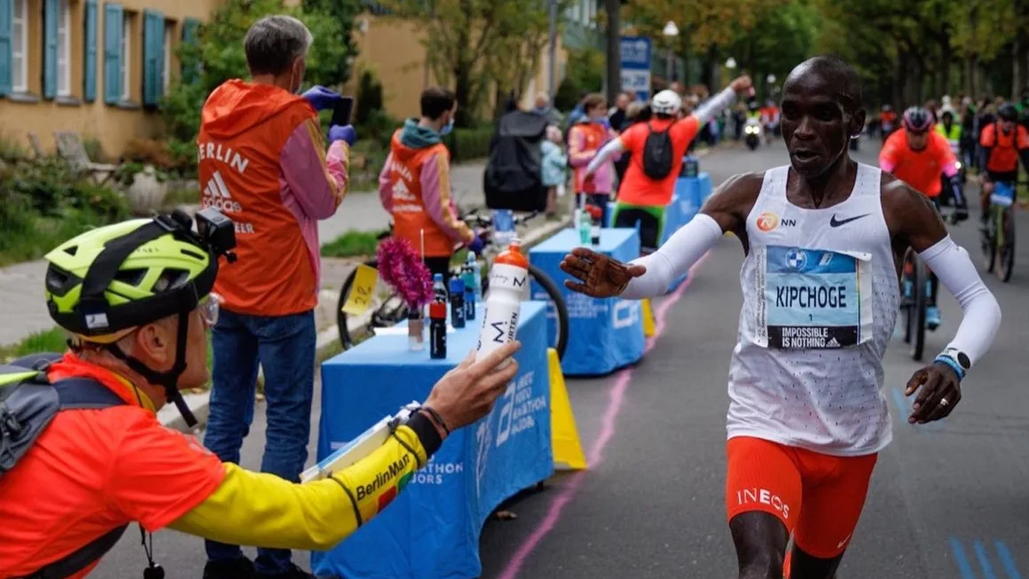 Claus pas&aacute;ndole el agua con sales a Kipchoge