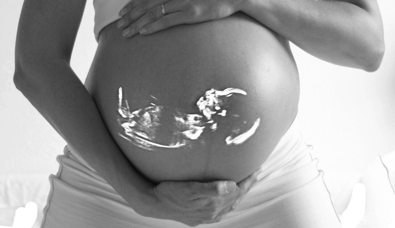 Una mujer embarazada, con el feto visto en su vientre a través de una radiografía
