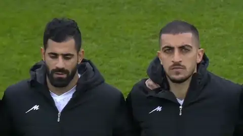 Los futbolistas tapan el escudo iraní mientras suena el himno de su país Los futbolistas tapan el escudo iraní mientras suena el himno de su país