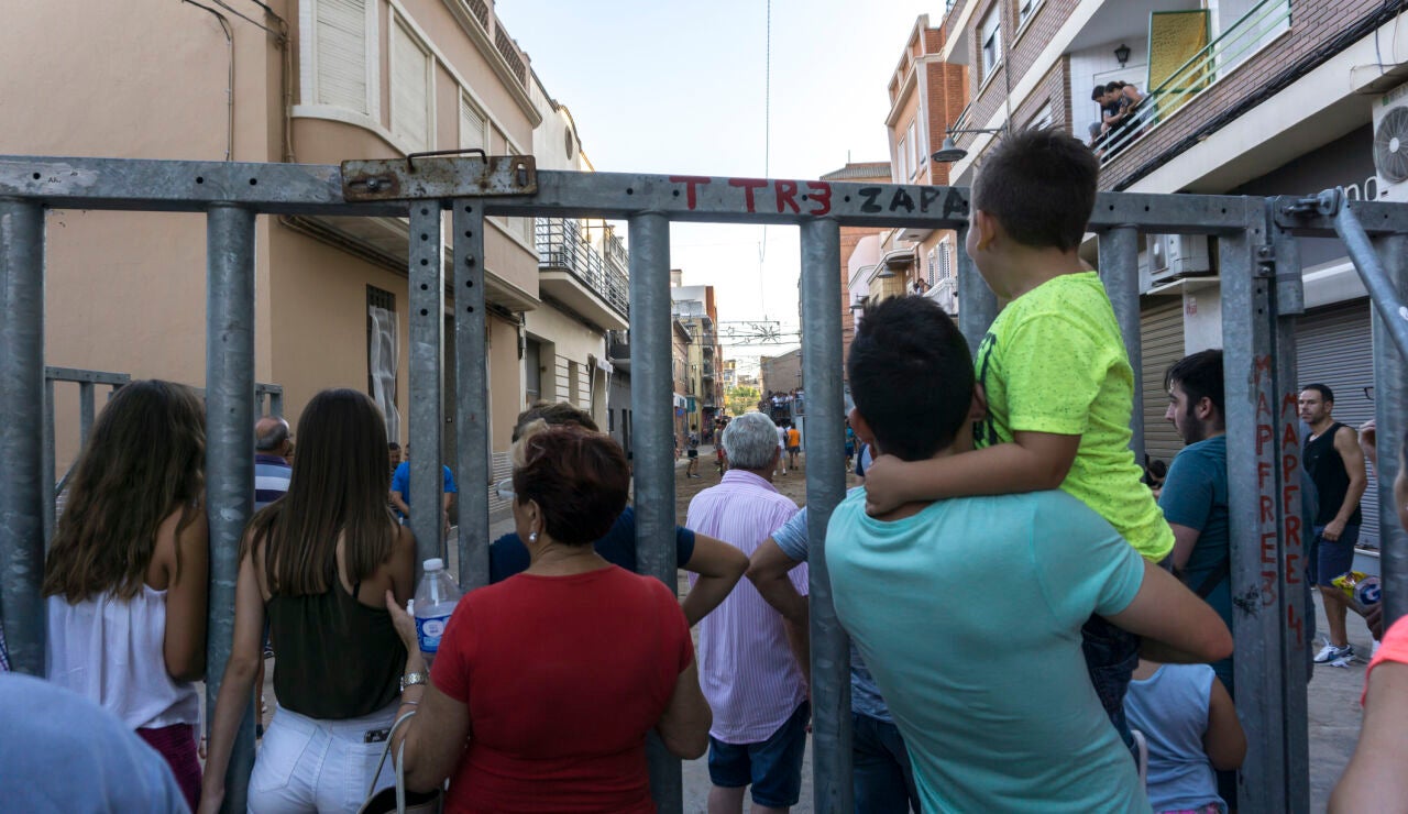 Personas apoyadas en una barrera de seguridad en un festejo taurino