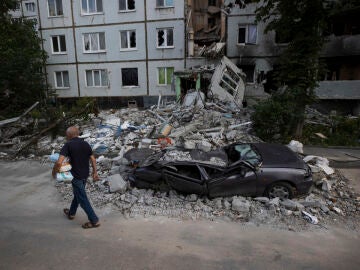 Imagen de archivo de un hombre caminando frente a destrozos por proyectiles rusos en el barrio Saltivka, en Járkov 