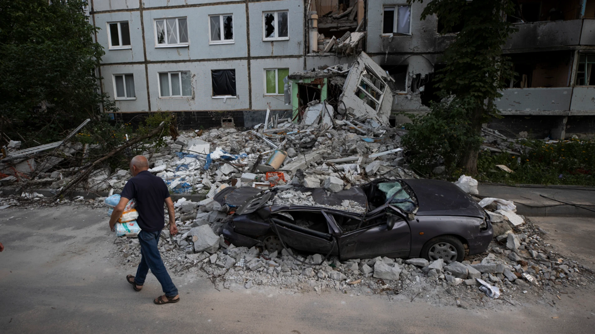 Imagen de archivo de un hombre caminando frente a destrozos por proyectiles rusos en el barrio Saltivka, en Járkov Imagen de archivo de un hombre caminando frente a destrozos por proyectiles rusos en el barrio Saltivka, en Járkov
