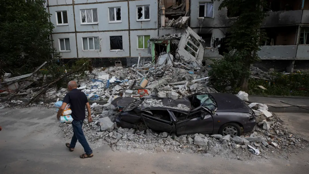 Imagen de archivo de un hombre caminando frente a destrozos por proyectiles rusos en el barrio Saltivka, en Járkov Imagen de archivo de un hombre caminando frente a destrozos por proyectiles rusos en el barrio Saltivka, en Járkov