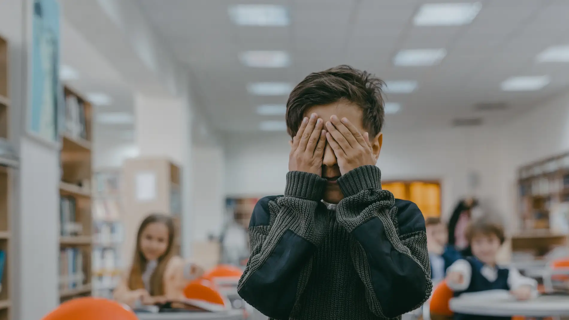Un niño se tapa la cara en el colegio.
