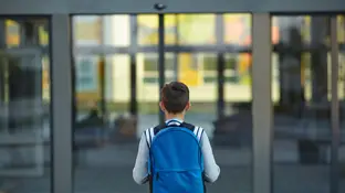 Un niño se acerca a la puerta de un colegio Un niño se acerca a la puerta de un colegio