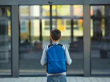 Un niño se acerca a la puerta de un colegio Un niño se acerca a la puerta de un colegio