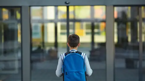 Un niño se acerca a la puerta de un colegio Un niño se acerca a la puerta de un colegio
