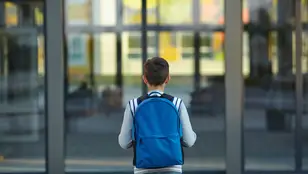 Un niño se acerca a la puerta de un colegio