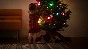 Una niña junto a su árbol de Navidad.