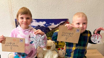 Dos niños ucranianos enfermos posan con sus cartas de Papá Noel