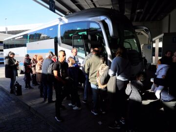 Varios viajeros esperan para poder acceder a un autobús