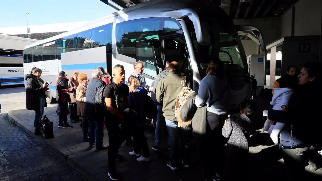 Varios viajeros esperan para poder acceder a un autob&uacute;s