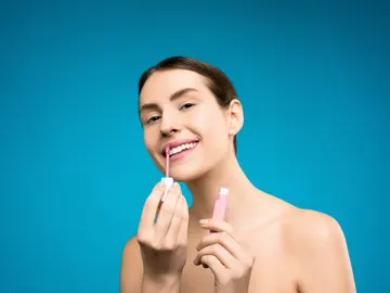 Chica se aplica gloss rosa en los labios Chica se aplica gloss rosa en los labios