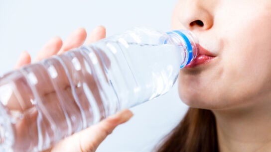 Mujer bebiendo de una botella de pl&aacute;stico
