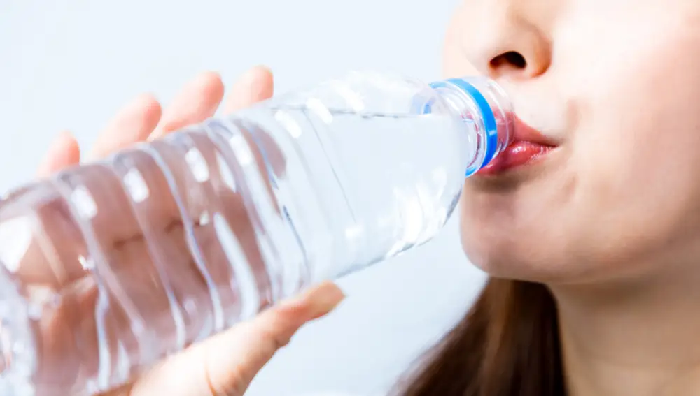 Mujer bebiendo de una botella de plástico