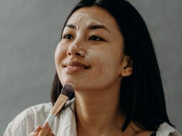 Joven asiática aplicándose una crema en el rostro