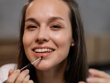 Mujer aplicándose aceite labial Mujer aplicándose aceite labial