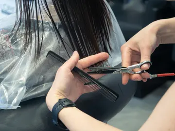 Primer plano de las manos de una peluquera cortando las puntas de una melena Primer plano de las manos de una peluquera cortando las puntas de una melena