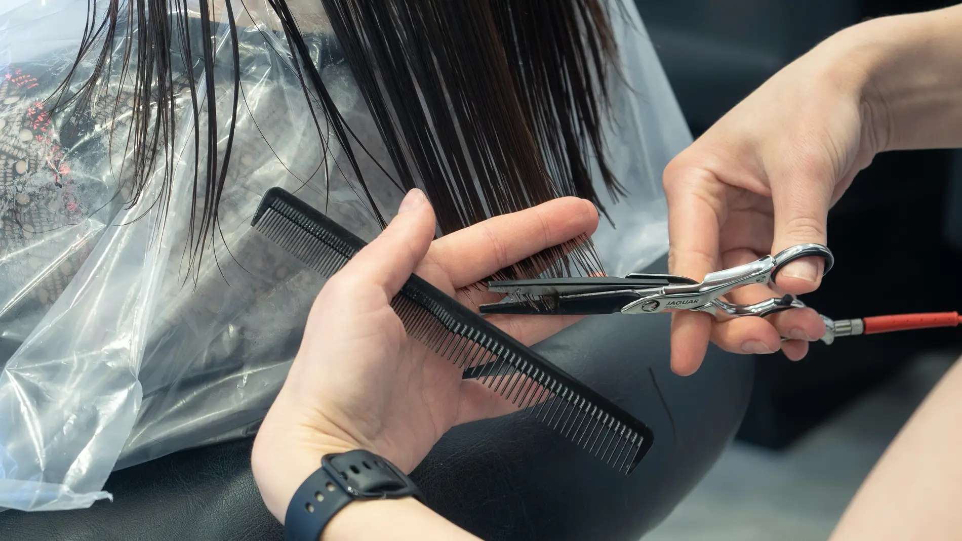 Primer plano de las manos de una peluquera cortando las puntas de una melena