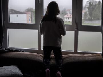 Una niña mirando por la ventana