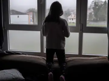 Una niña mirando por la ventana Una niña mirando por la ventana
