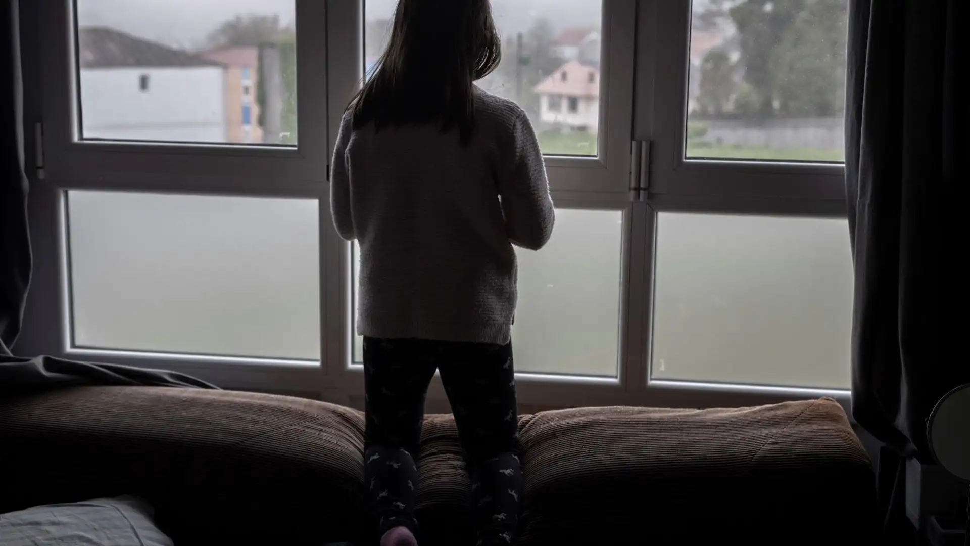 Una niña mirando por la ventana Una niña mirando por la ventana