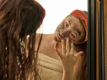 Chica aplicándose una mascarilla facial Chica aplicándose una mascarilla facial