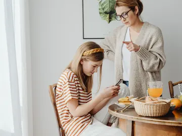 Una adolescente con el móvil bajo la mirada de su madre Una adolescente con el móvil bajo la mirada de su madre