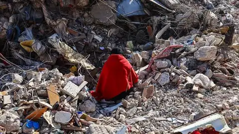 Una mujer sobre los escombros de su casa Una mujer sobre los escombros de su casa