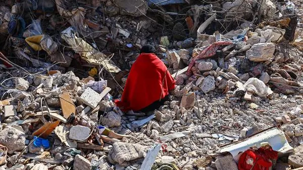 Una mujer sobre los escombros de su casa Una mujer sobre los escombros de su casa