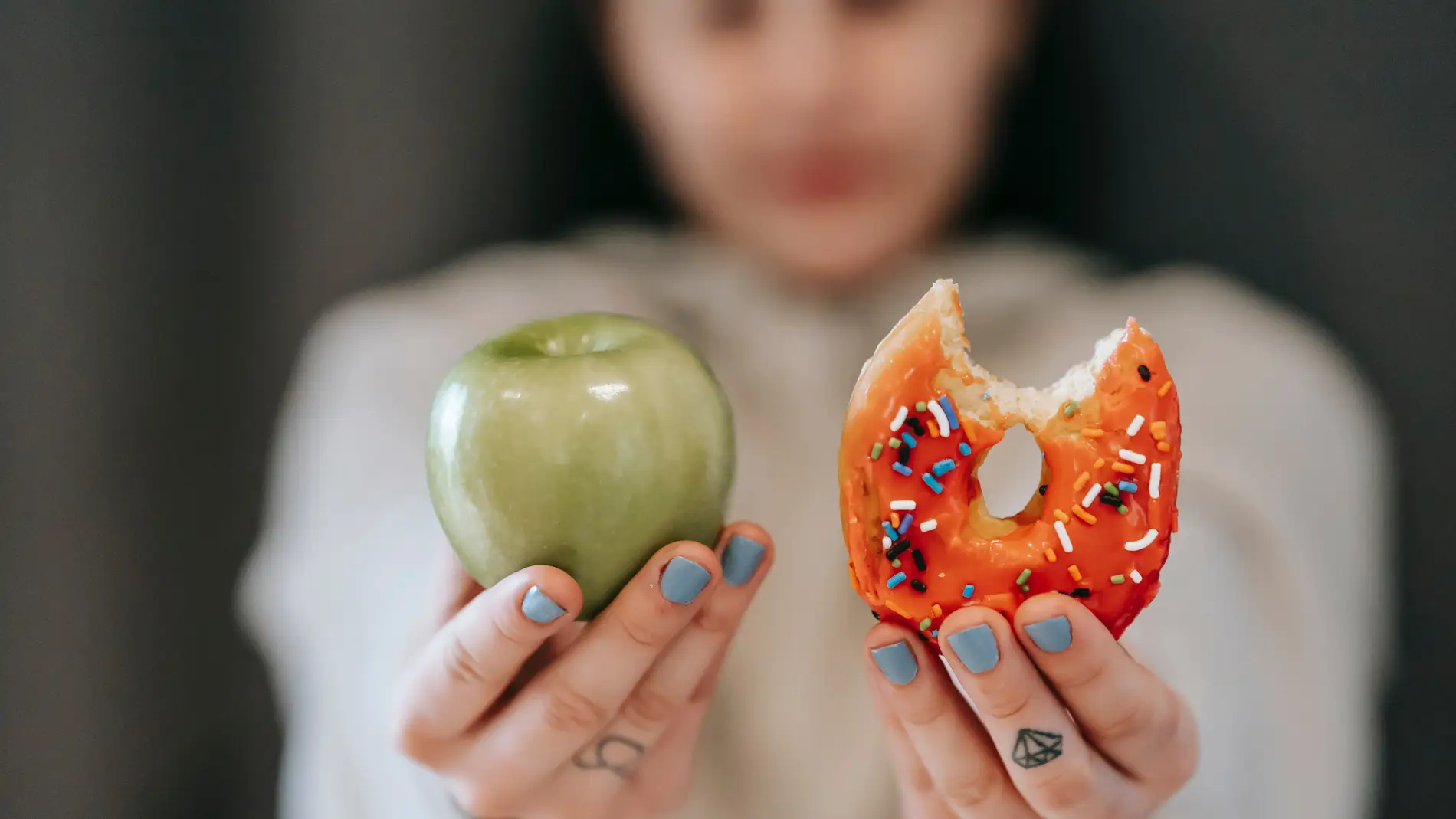 Una mujer sostiene una fruta y un dulce