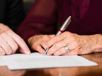 Una persona mayor firma un documento