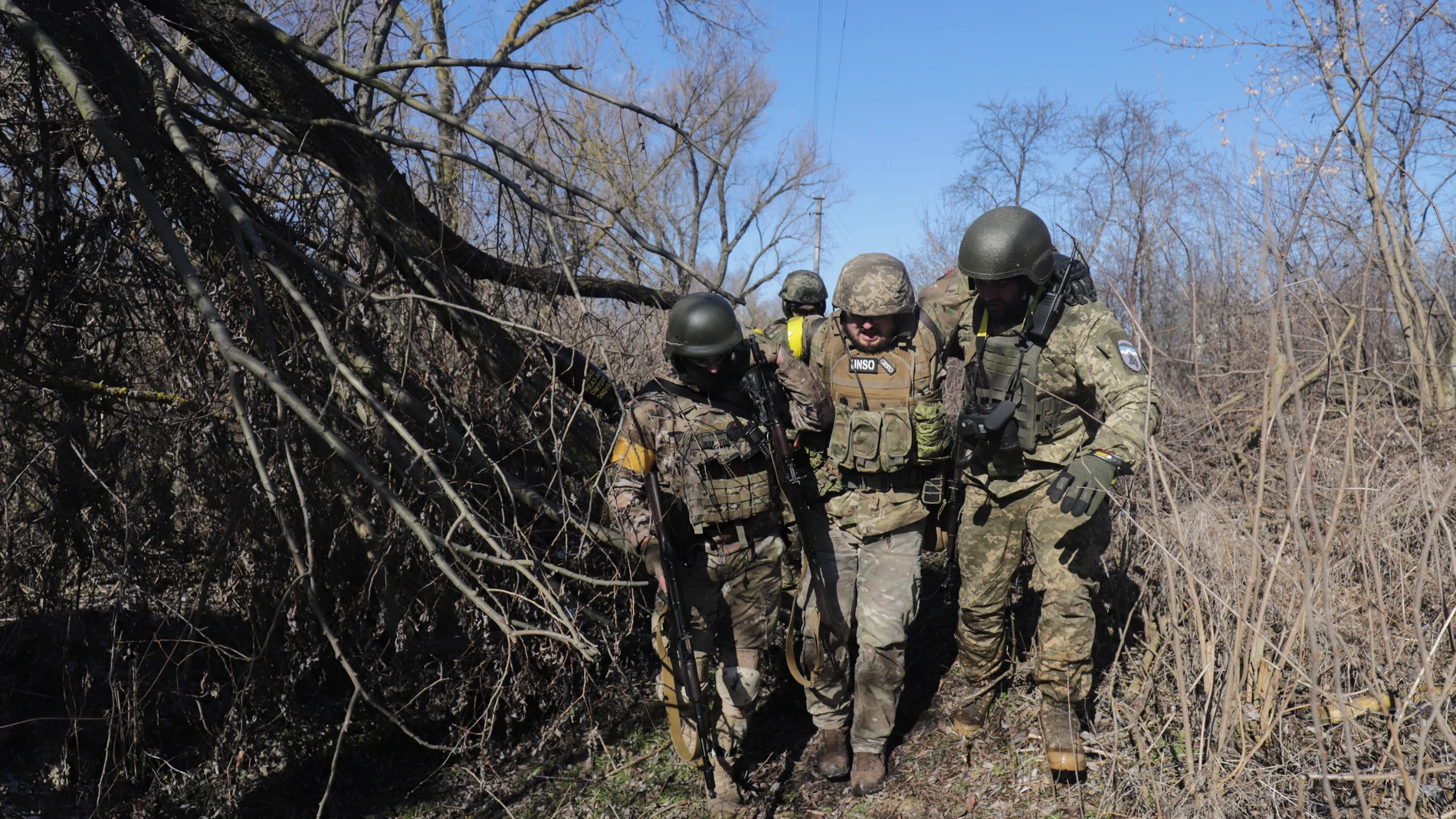 Varios militares ucranianos ayudan a un compañero herido