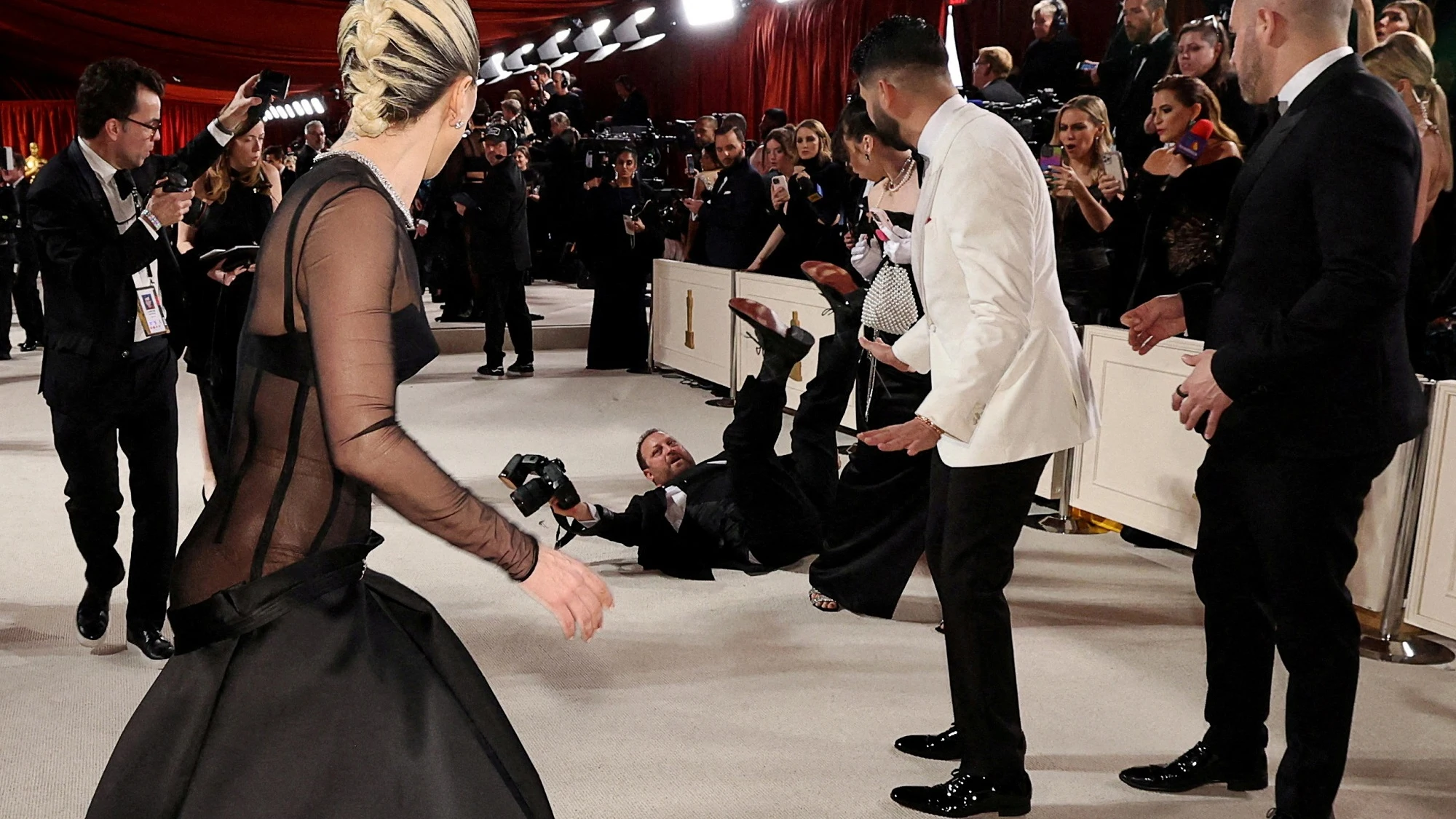 Lady Gaga ayuda a un fot&oacute;grafo en la alfombra roja de los Oscar