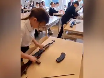 Una niña aprende a montar un fusil en un colegio