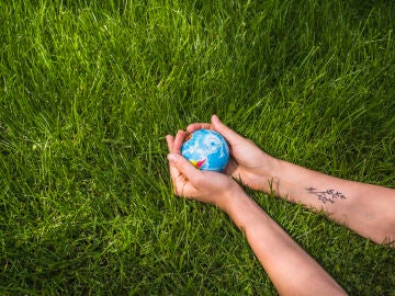 Una mujer sostiene la bola del globo en la hierba verde