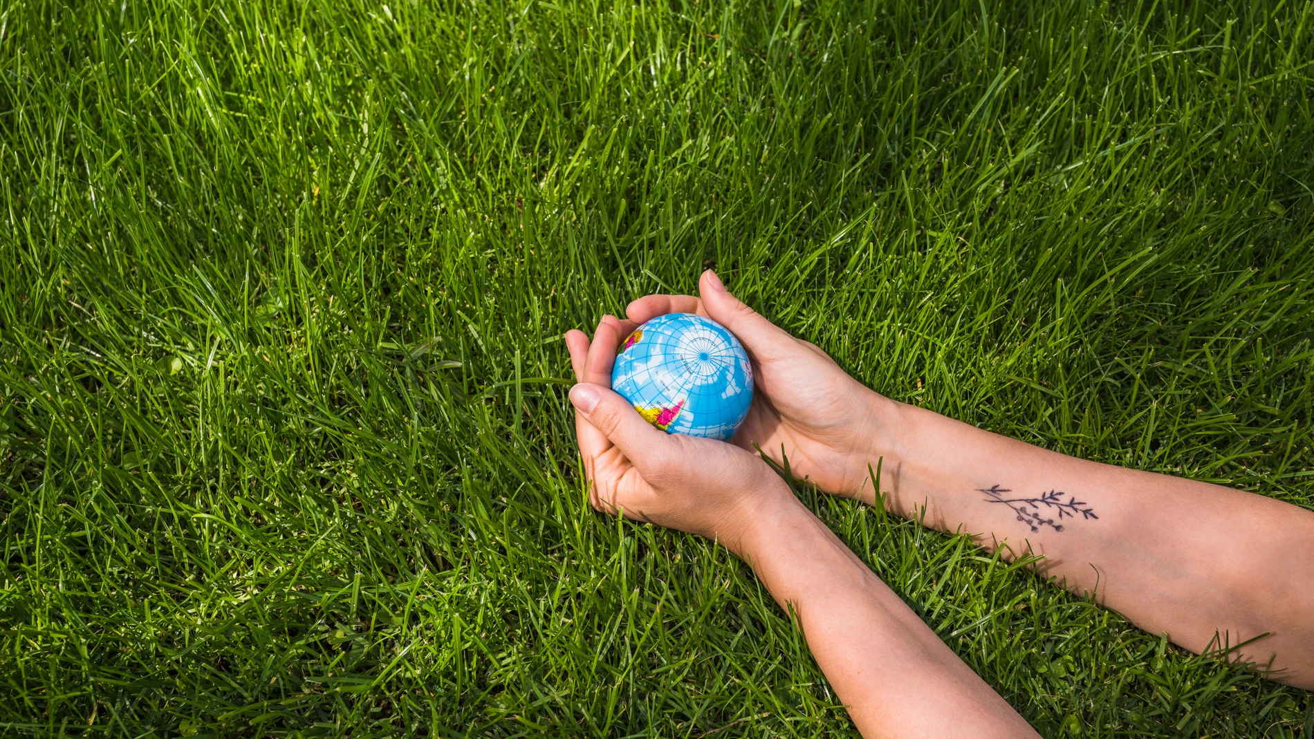 Una mujer sostiene la bola del globo en la hierba verde