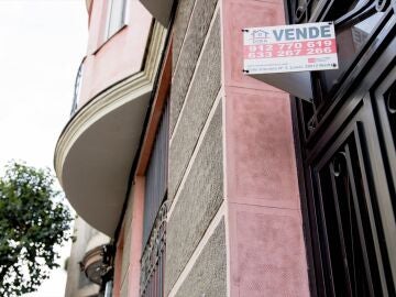 Un cartel de 'Vende' de una inmobiliaria en el portal de un edificio