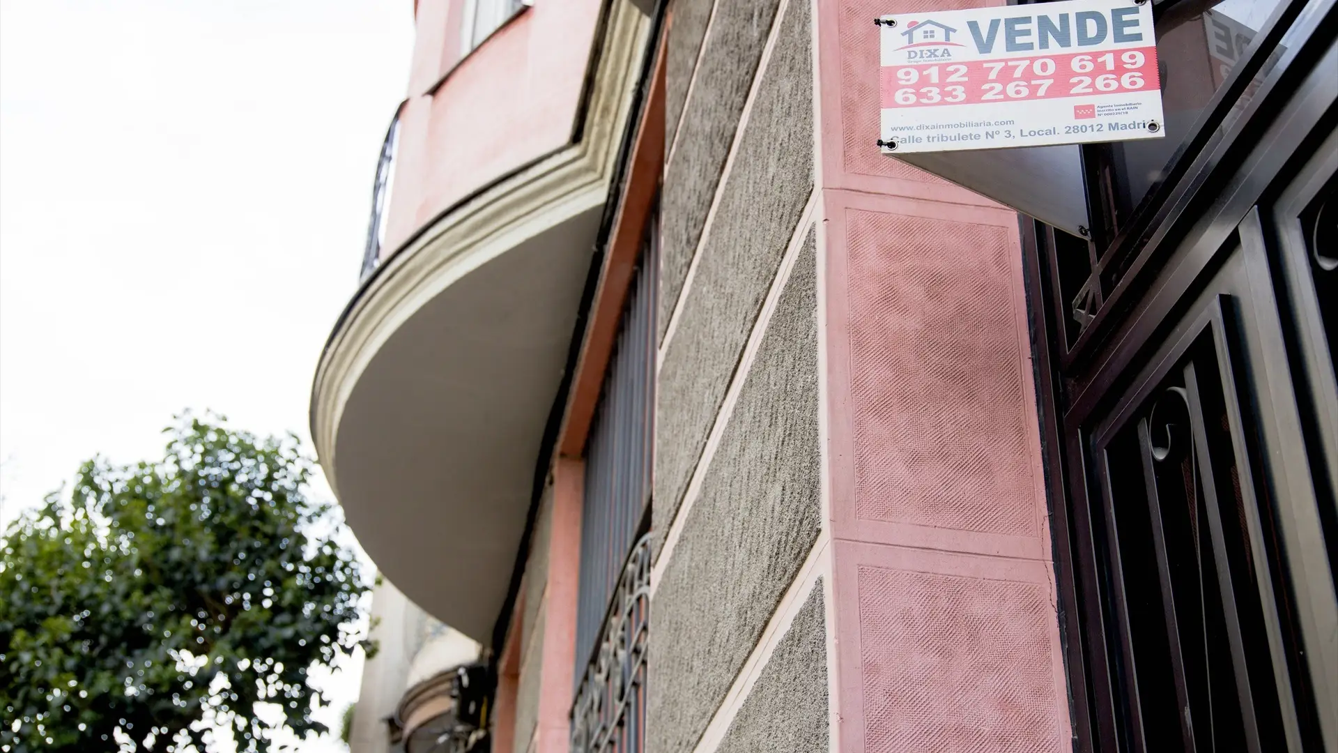 Un cartel de 'Vende' de una inmobiliaria en el portal de un edificio