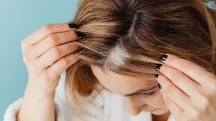 Mujer con canas mir&aacute;ndose al espejo